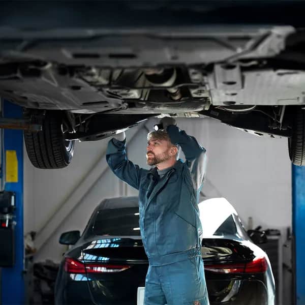 Ein Mechaniker bei der Arbeit unter dem Fahrzeug – regelmäßige Motorinnenreinigung kann teure Reparaturen vermeiden und für einen ruhigeren Motorlauf sorgen.